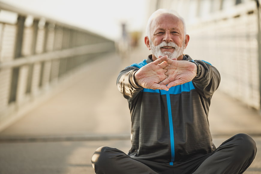 Senior man stretching outdoors on a bridge