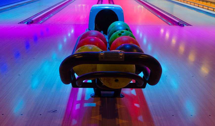 Colorful Bowling Balls in Rack on Neon Lit Lane