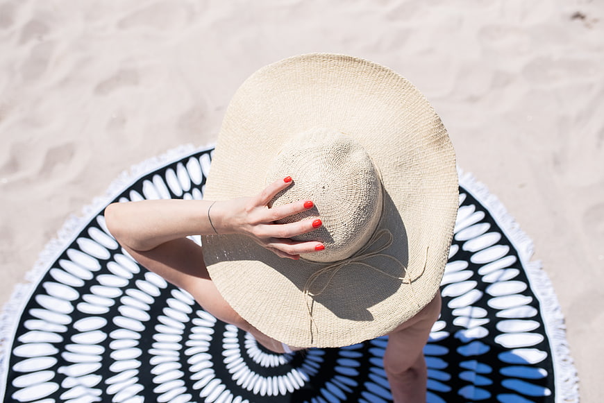 Top view of woman in straw hat on beach towel