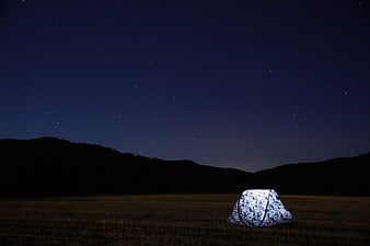 Illuminated Camping Tent Under Starry Night Sky in Field