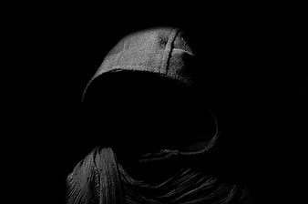 Mysterious hooded figure in darkness with obscured face