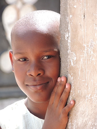 Close-up portrait of smiling African girl leaning against wall