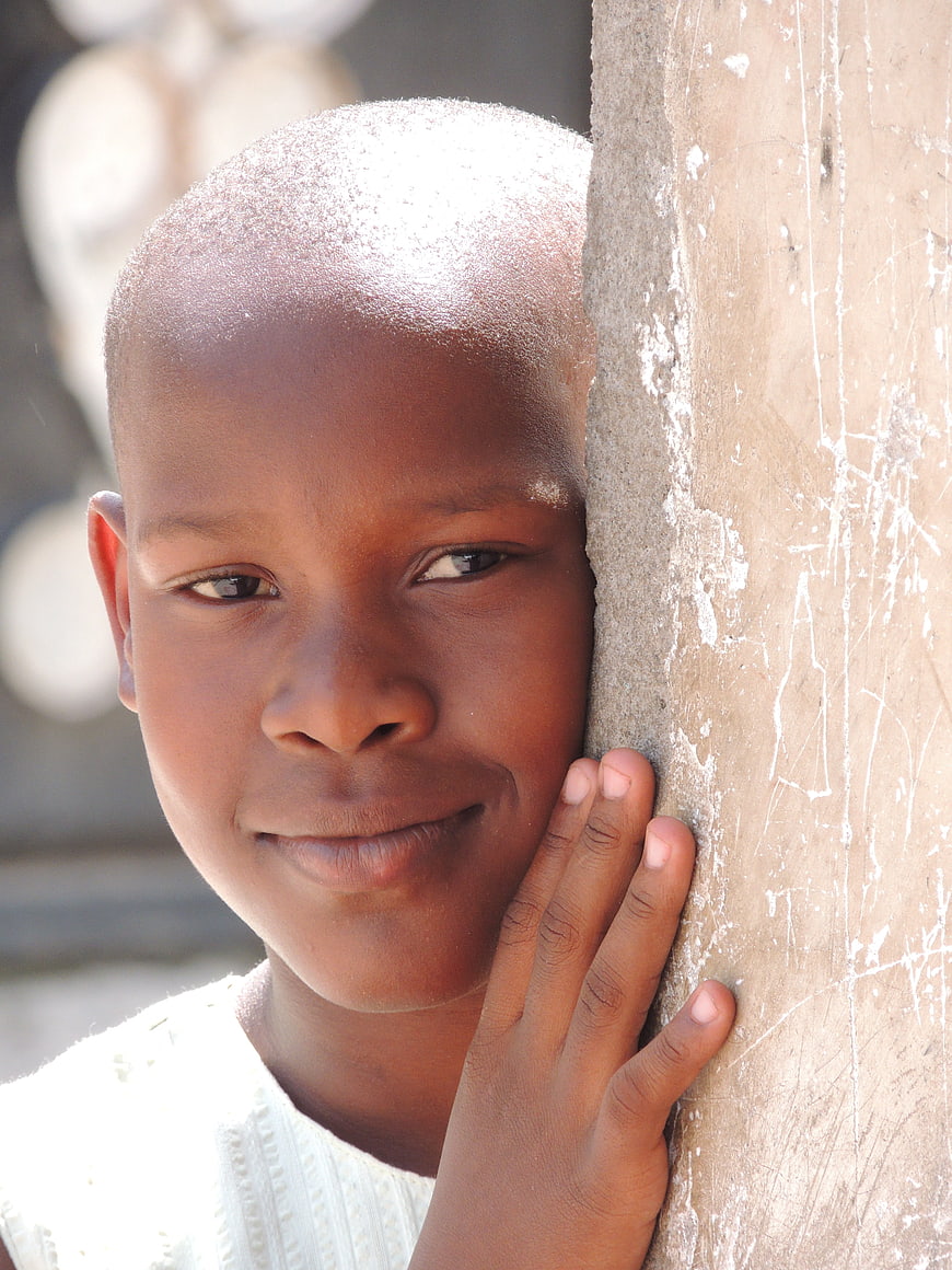 Close-up portrait of smiling African girl leaning against wall