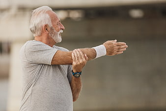 Senior man stretching arm outdoors for fitness