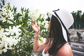 Woman in White Hat Smelling White Oleander Flowers