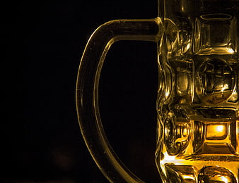 Close-up of golden beer in textured glass mug handle