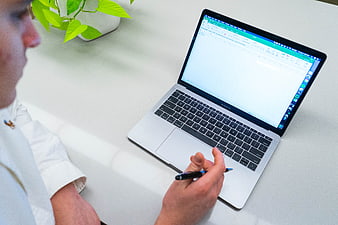 Man working on laptop with spreadsheet and pen