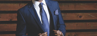 Man in Blue Suit Adjusting Jacket Against Wooden Background