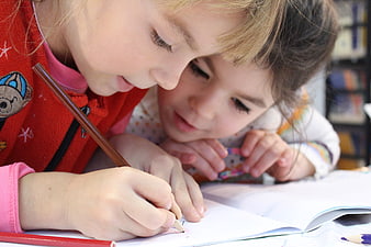 Two young girls drawing and studying together in a library