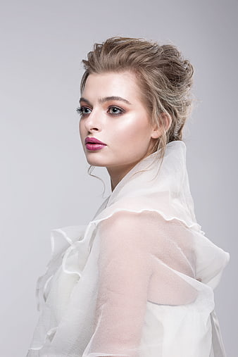 Elegant female fashion portrait with soft studio lighting and white ruffled top