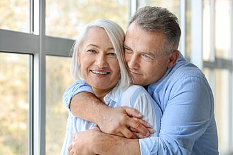 Happy Senior Couple Embracing by Window