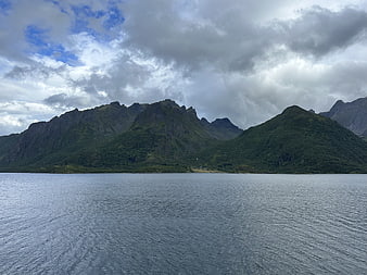 Dramatic Green Mountains and Cloudy Sky Over Calm Water