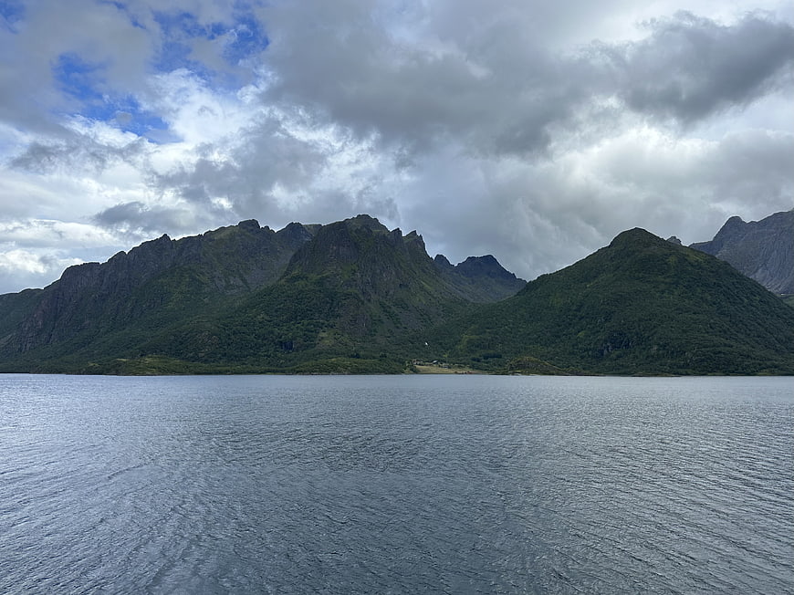 Dramatic Green Mountains and Cloudy Sky Over Calm Water