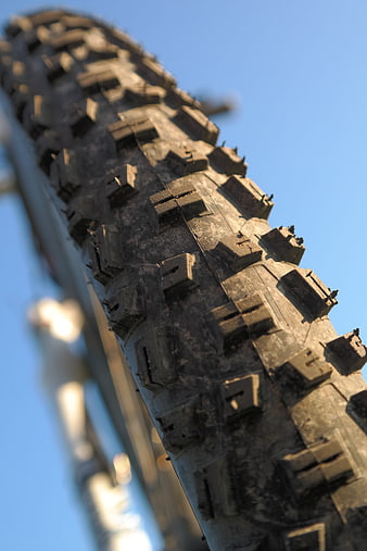 Close-up of rugged mountain bike tire tread against blue sky