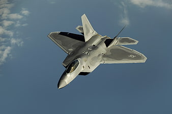 F-22 Raptor fighter jet flying against blue sky