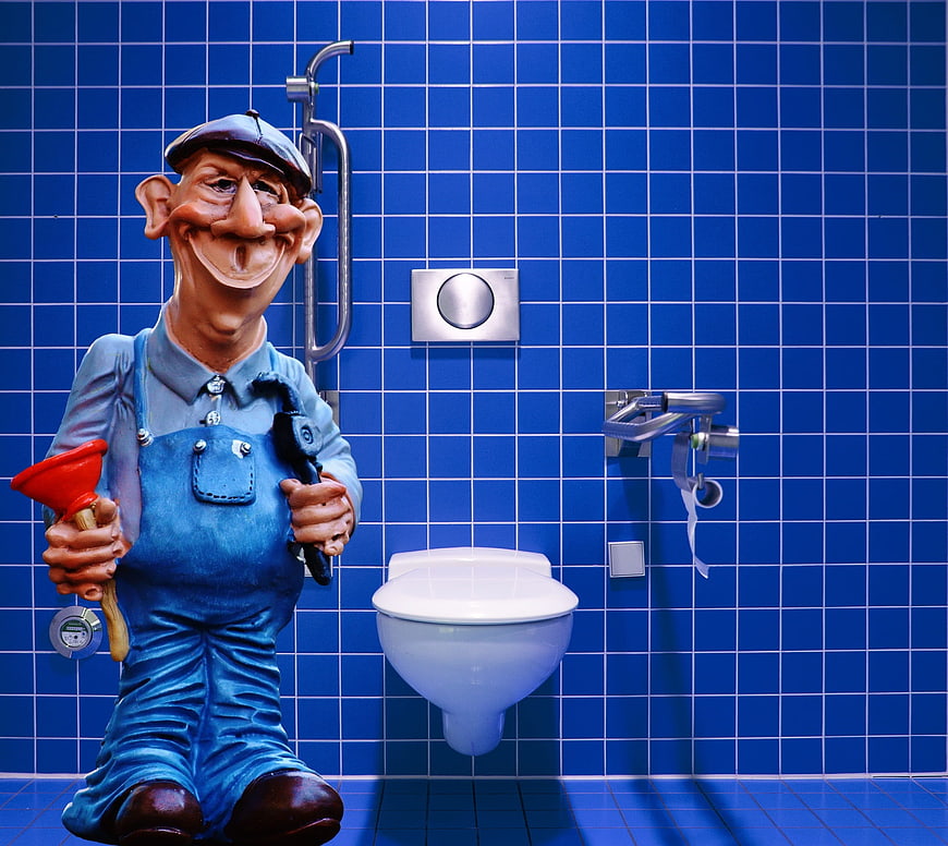 Plumber figurine with plunger in blue tiled bathroom