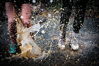 Runners splashing through muddy puddles in rain