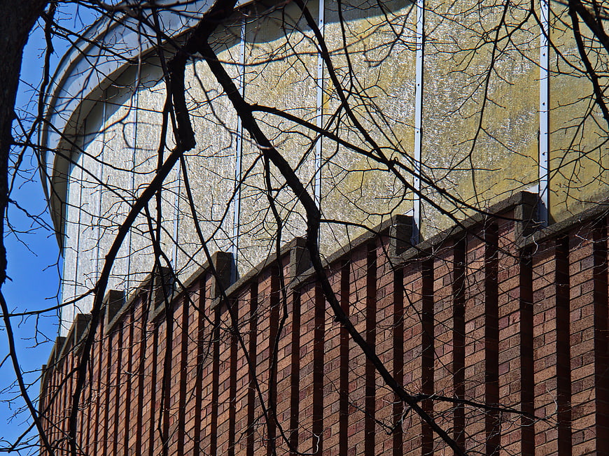 Modern curved building facade with brick wall and bare branches