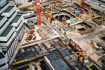 Aerial view of large urban construction site with cranes and excavators