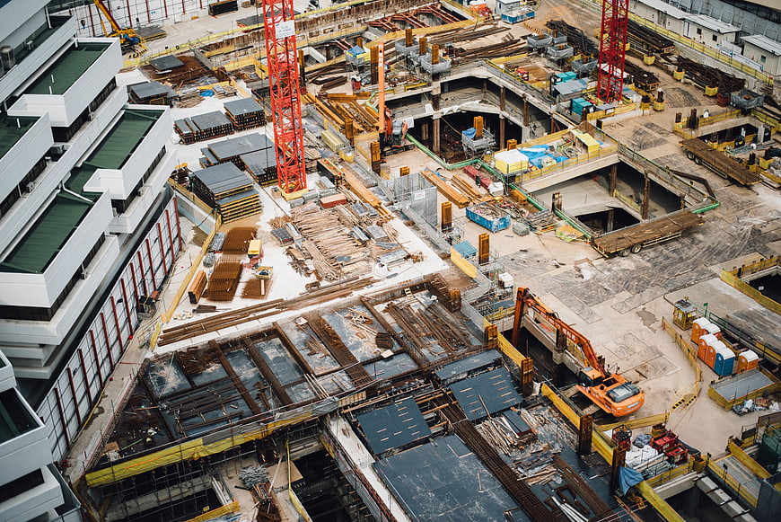 Aerial view of large urban construction site with cranes and excavators