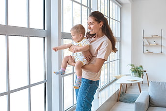 Happy Mother Holding Toddler Boy Looking Out Large Window