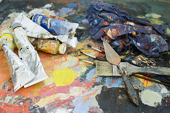 Used paint tubes, brushes, and palette knife on messy artist table