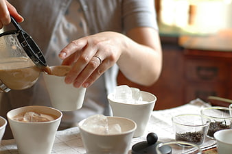 Woman pouring iced tea into white cups on a table