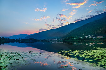 Serene lake reflection with sunset clouds and mountains