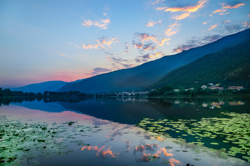 Serene lake reflection with sunset clouds and mountains
