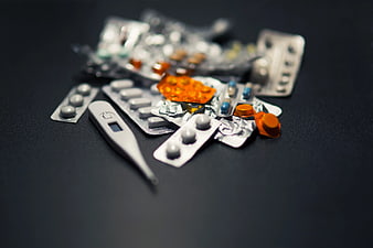 Assorted Medicines and Digital Thermometer on Dark Background