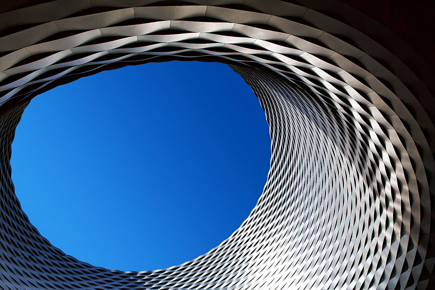 Abstract modern architecture with curved white lattice against blue sky