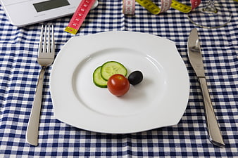 Healthy diet concept with minimal food on white plate and measuring tape