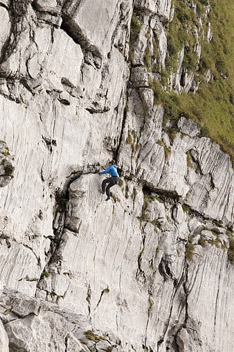Rock climber scaling steep limestone cliff face outdoors