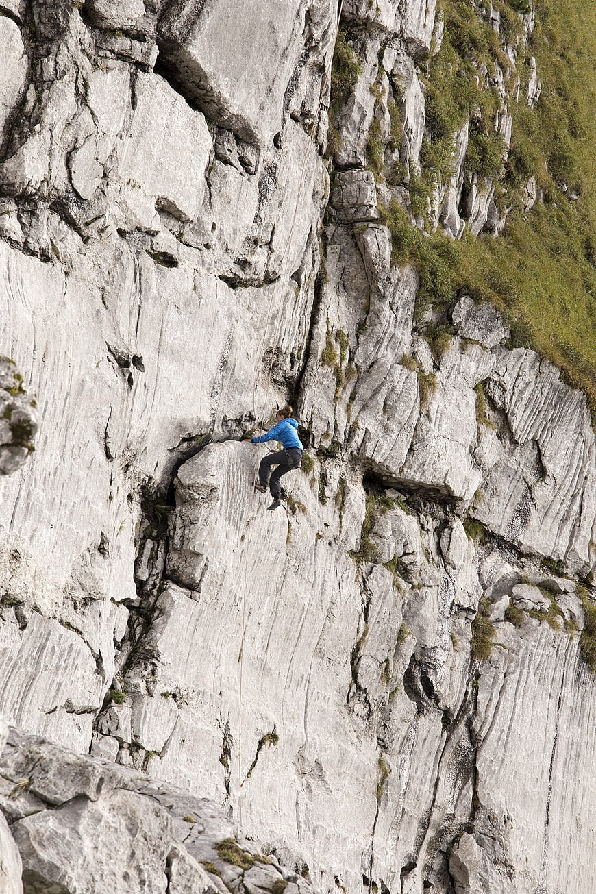 Rock climber scaling steep limestone cliff face outdoors