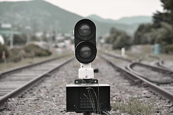 Vintage railway signal light centered on train tracks with blurred background