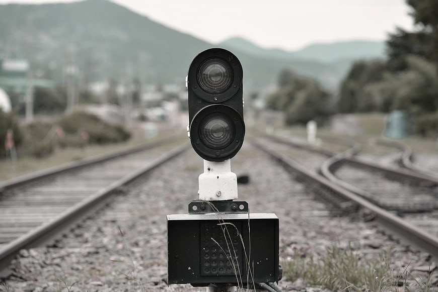 Vintage railway signal light centered on train tracks with blurred background