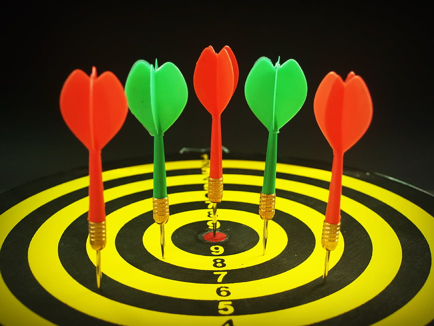 Five darts stuck in a dartboard bullseye