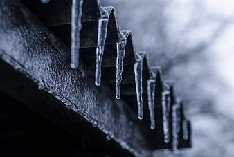 Close-up of icicles hanging from a dark roof edge