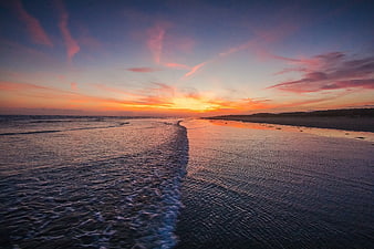 Serene Sunset Over Ocean Beach with Pink Clouds