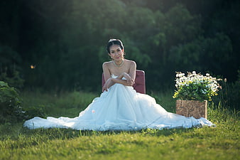 Asian Bride in White Gown Sitting on Grass Outdoors