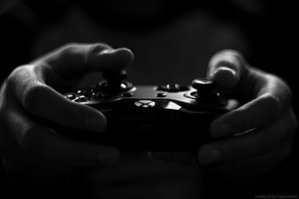 Hands holding video game controller in black and white