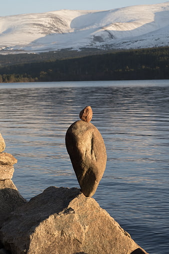 Balanced stones by lake with snowy mountains