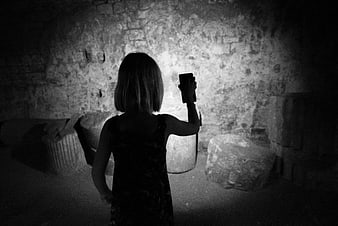 Woman holding smartphone flashlight in dark stone cellar