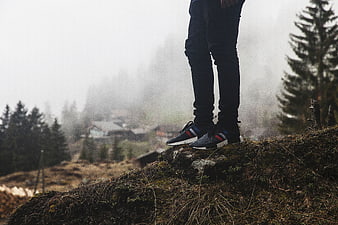 Hiker standing on rocky cliff edge in foggy forest