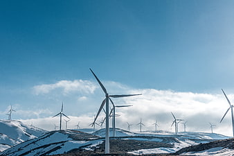 Wind turbines on snowy mountain ridge under blue sky