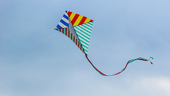 Colorful Striped Kite Flying High In Blue Sky