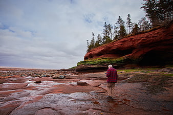 Senior man hiking on red sandstone coastal cliffs