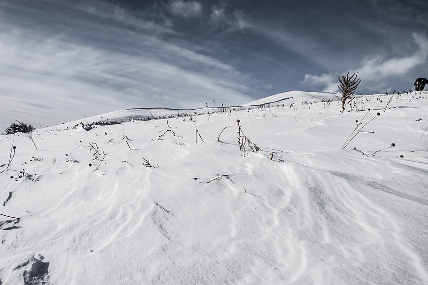 Snowy winter landscape with wind-swept hills and blue sky