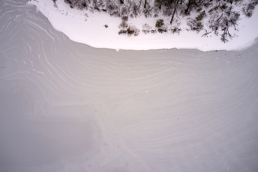 Aerial view of frozen lake with snow and trees