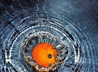 Orange Dropping Into Water With Dramatic Blue Splash